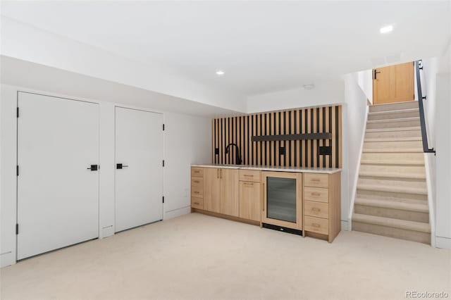 kitchen with light brown cabinetry, beverage cooler, light colored carpet, recessed lighting, and a sink