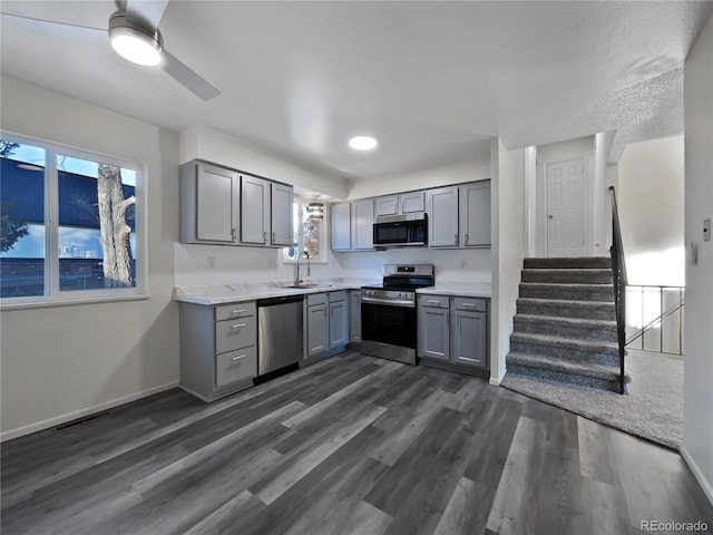 kitchen featuring appliances with stainless steel finishes, gray cabinets, a sink, and dark wood-style floors