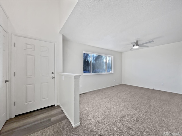 foyer entrance with ceiling fan, baseboards, a textured ceiling, and carpet flooring