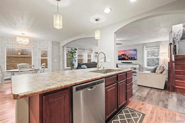 3677 Reindeer Cir, Colorado Springs, CO 80922 - kitchen with stainless steel dishwasher, open floor plan, a sink, arched walkways, and light wood-style floors