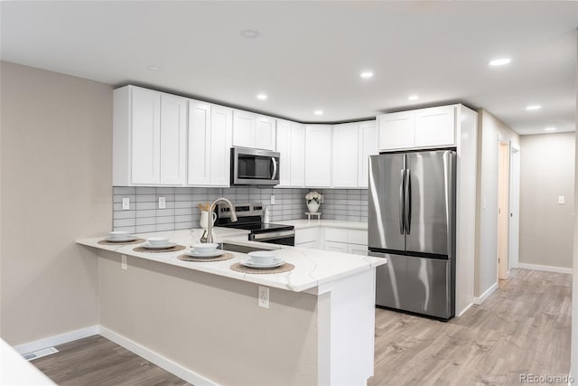 kitchen featuring stainless steel appliances, light wood-style flooring, and white cabinets