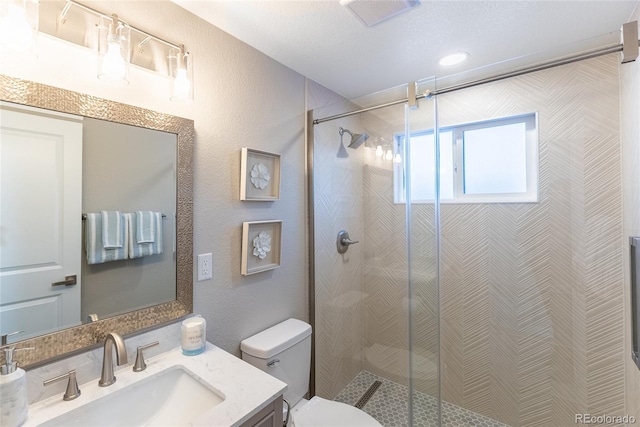 bathroom with visible vents, a textured wall, toilet, a stall shower, and vanity