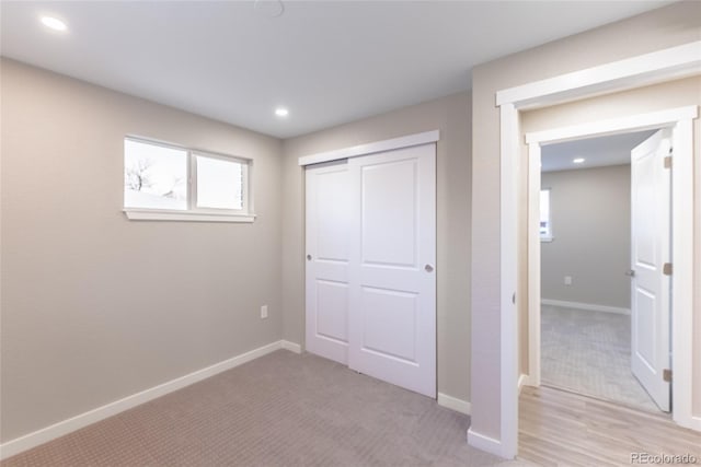 unfurnished bedroom with baseboards, a closet, and light colored carpet