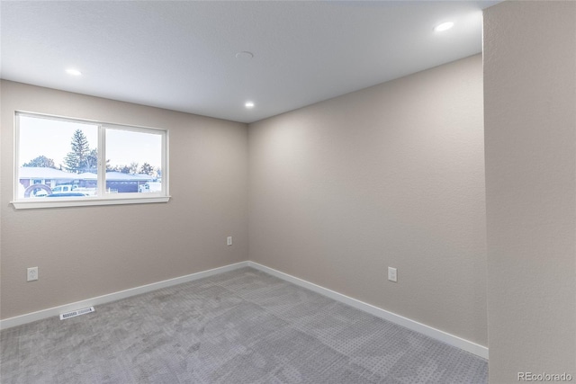 spare room featuring light carpet, recessed lighting, visible vents, and baseboards