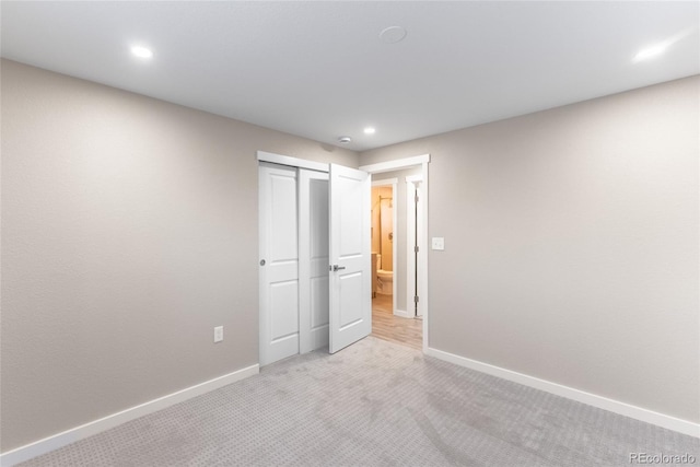 unfurnished bedroom featuring recessed lighting, a closet, light colored carpet, and baseboards