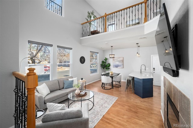 living room featuring sink, light hardwood / wood-style floors, and a towering ceiling