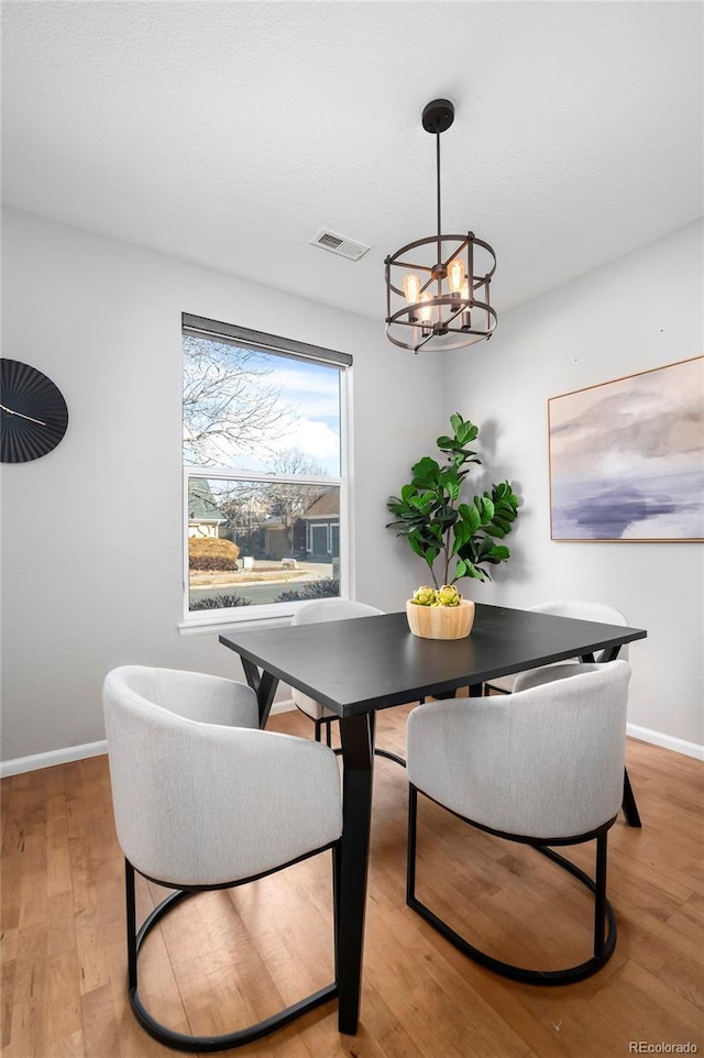 dining room with an inviting chandelier and light hardwood / wood-style flooring