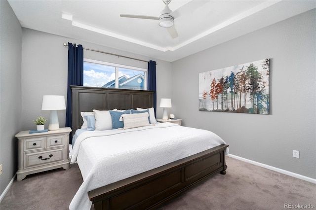 carpeted bedroom with a raised ceiling and ceiling fan