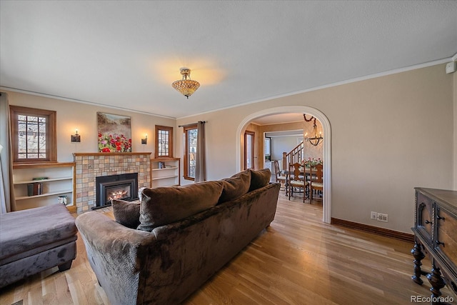 living room featuring a chandelier, crown molding, a fireplace, and light hardwood / wood-style floors