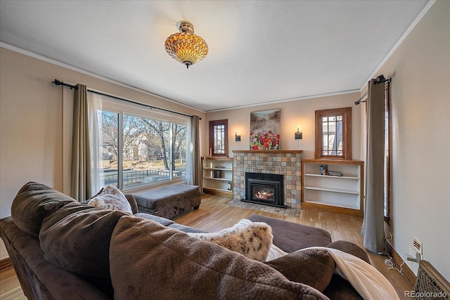 living room with a fireplace, crown molding, plenty of natural light, and light hardwood / wood-style floors