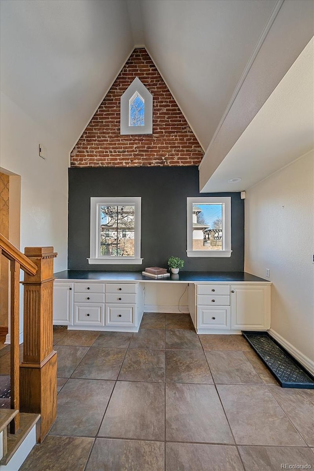 bathroom with lofted ceiling and brick wall