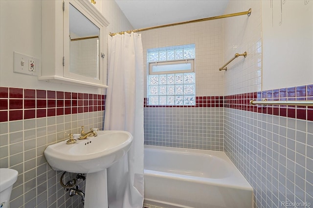 bathroom featuring shower / bath combo, toilet, and tile walls