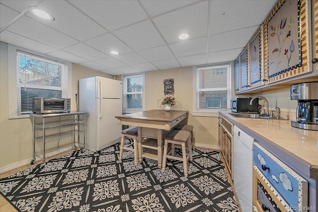 kitchen featuring a drop ceiling, white appliances, and sink