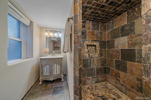 bathroom featuring vanity, a tile shower, and a wealth of natural light