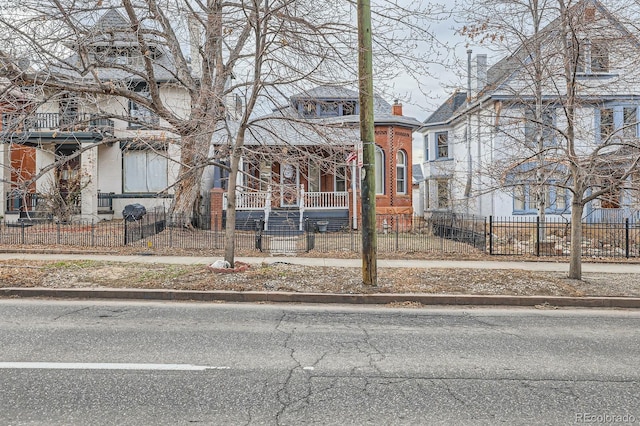 view of front of house featuring a fenced front yard, a porch, and a chimney