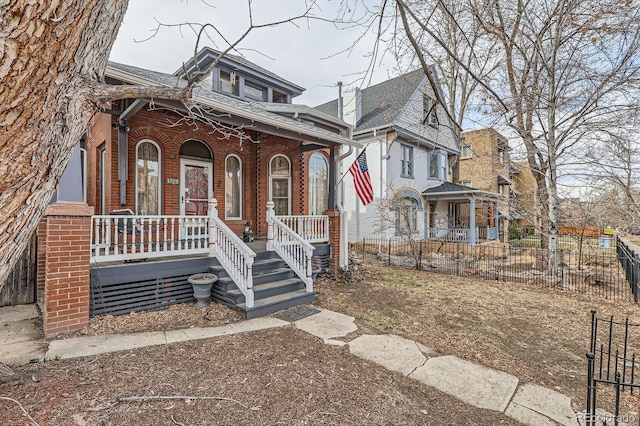 view of front of house featuring brick siding, covered porch, and fence