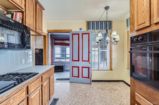 kitchen with a notable chandelier, brown cabinets, light floors, and black appliances