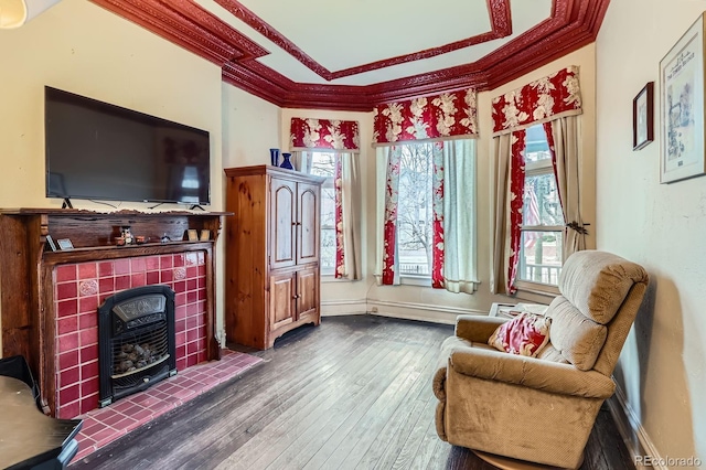 living area with baseboards, wood-type flooring, and ornamental molding