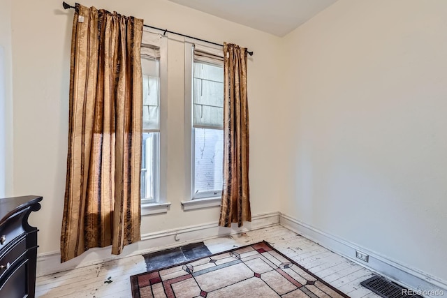 unfurnished room featuring plenty of natural light, light wood-type flooring, baseboards, and a wood stove