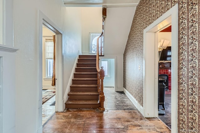 staircase with wallpapered walls, a wealth of natural light, baseboards, and wood-type flooring