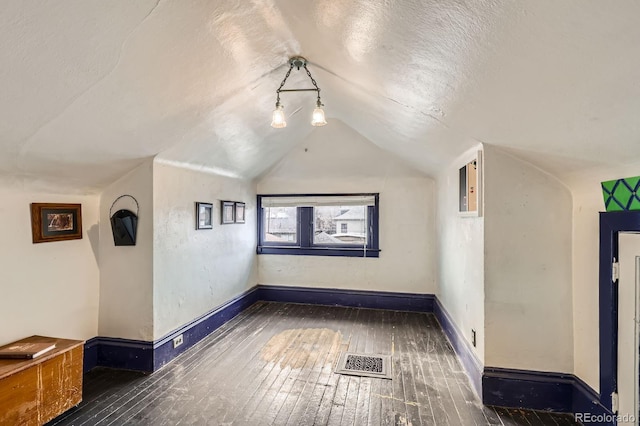 bonus room with visible vents, a textured ceiling, lofted ceiling, and hardwood / wood-style flooring