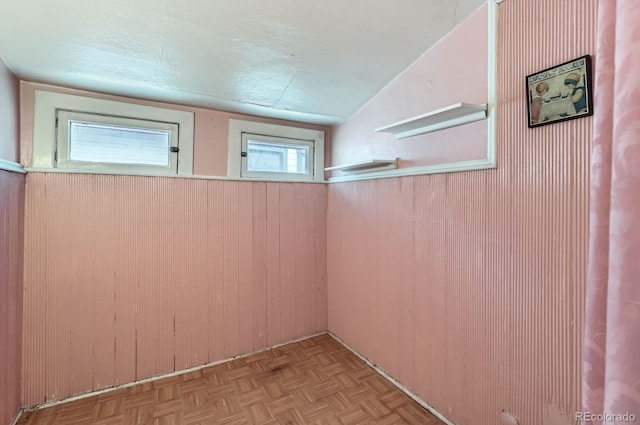 spare room with wood walls, a textured ceiling, and vaulted ceiling