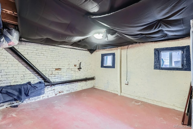 basement with a healthy amount of sunlight and brick wall