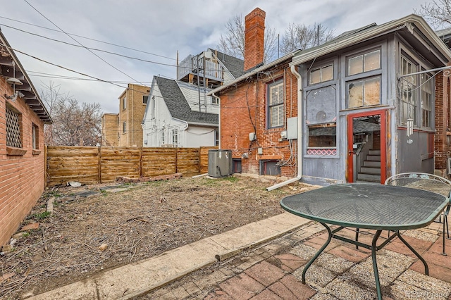 back of house featuring brick siding, a chimney, a patio, and fence