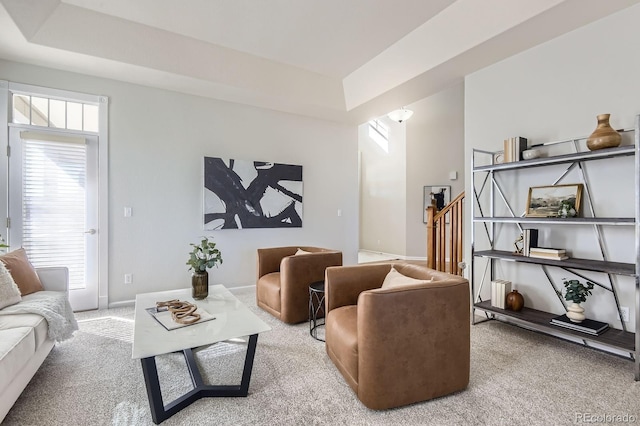 living room with a tray ceiling, carpet floors, baseboards, and stairs