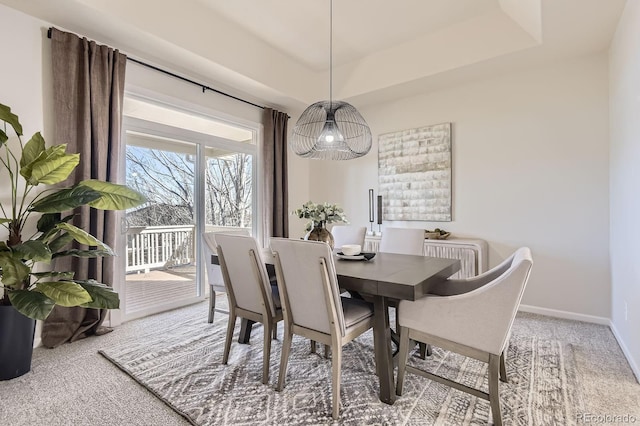 dining room featuring baseboards, a raised ceiling, and carpet flooring