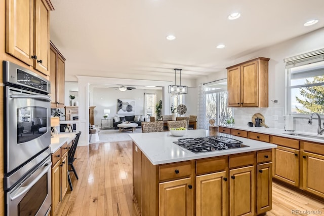 kitchen with double oven, black gas stovetop, light countertops, and a sink