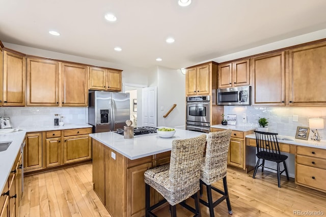 kitchen with light wood-style flooring, appliances with stainless steel finishes, a center island, and a kitchen breakfast bar