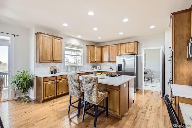 kitchen with a kitchen island, light countertops, brown cabinets, light wood-style floors, and a sink