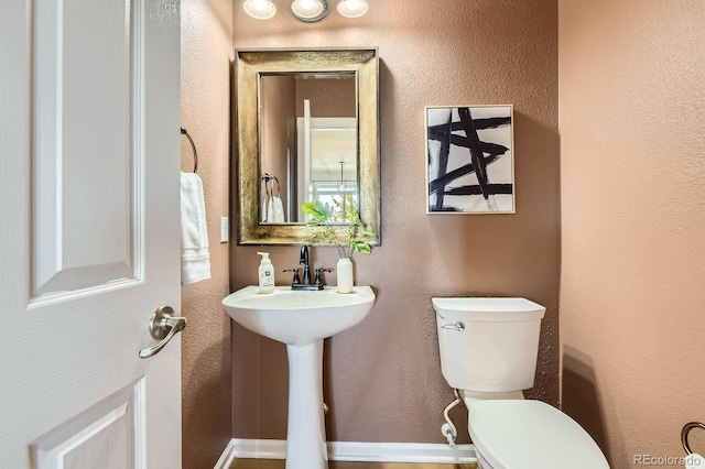 half bathroom featuring toilet and a textured wall