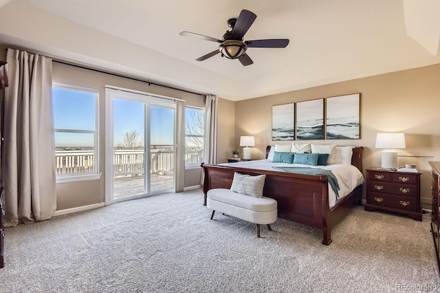 carpeted bedroom featuring baseboards, a raised ceiling, access to exterior, and a ceiling fan