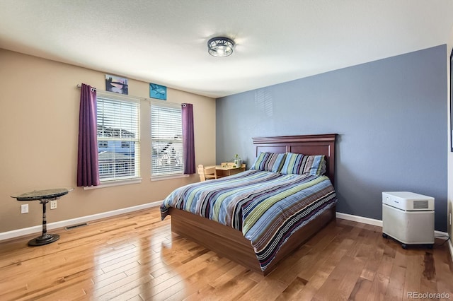 bedroom with visible vents, baseboards, and wood finished floors