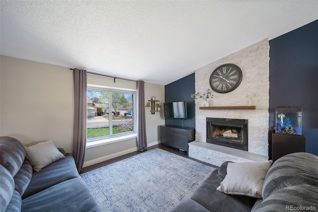 living room featuring a fireplace, a textured ceiling, baseboards, wood finished floors, and lofted ceiling