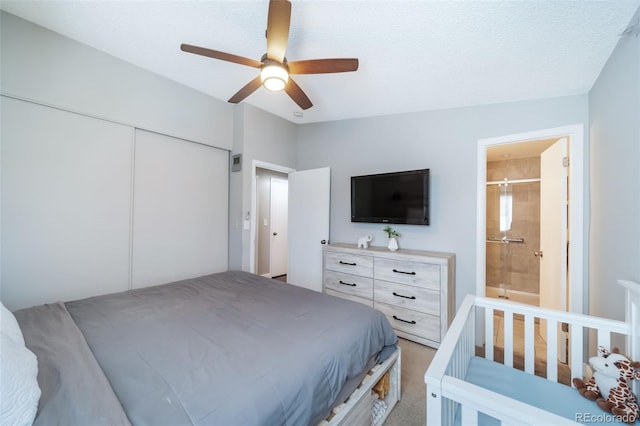 bedroom featuring ceiling fan, ensuite bathroom, a closet, and light carpet