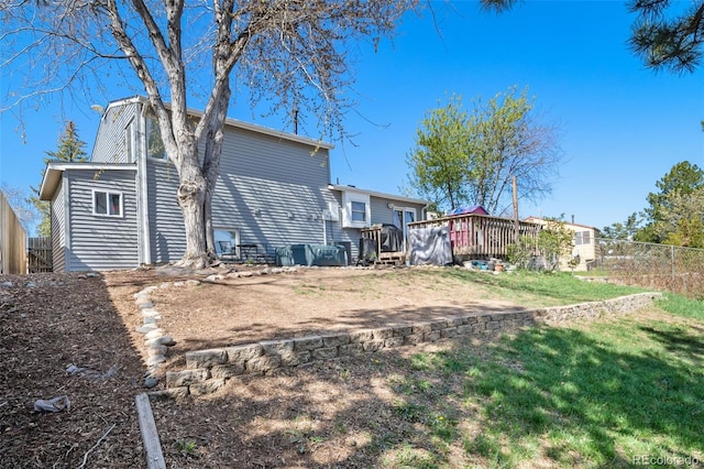back of property with a lawn, fence, and a wooden deck