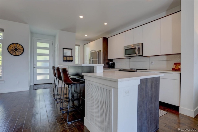 kitchen featuring white cabinets, a kitchen breakfast bar, a kitchen island, and dark hardwood / wood-style flooring