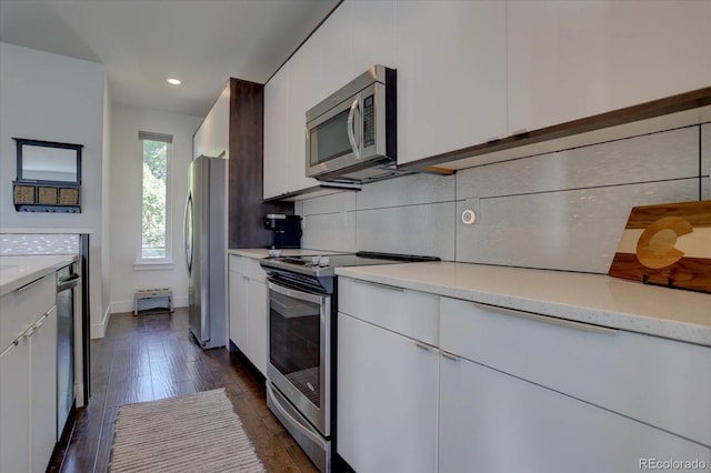 kitchen featuring stainless steel appliances, tasteful backsplash, light stone counters, dark hardwood / wood-style floors, and white cabinets