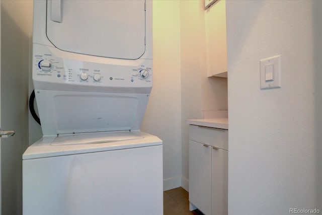 washroom with light tile patterned flooring, cabinets, and stacked washing maching and dryer