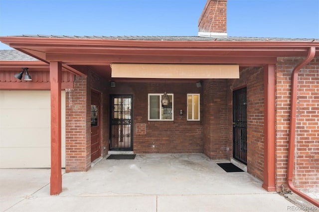 property entrance featuring a garage, brick siding, and a chimney