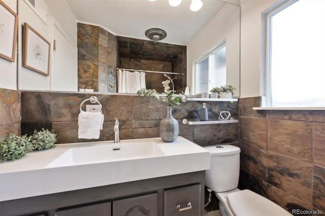 full bathroom with toilet, curtained shower, vanity, and tile walls