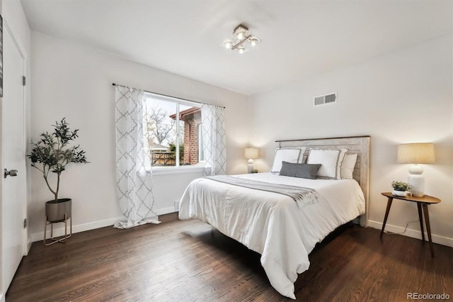 bedroom featuring baseboards, visible vents, and wood finished floors