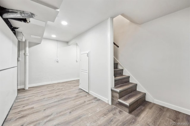 finished basement featuring recessed lighting, stairway, baseboards, and wood finished floors