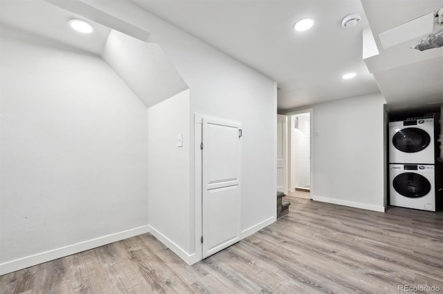 laundry room featuring laundry area, baseboards, stacked washer / dryer, light wood-type flooring, and recessed lighting