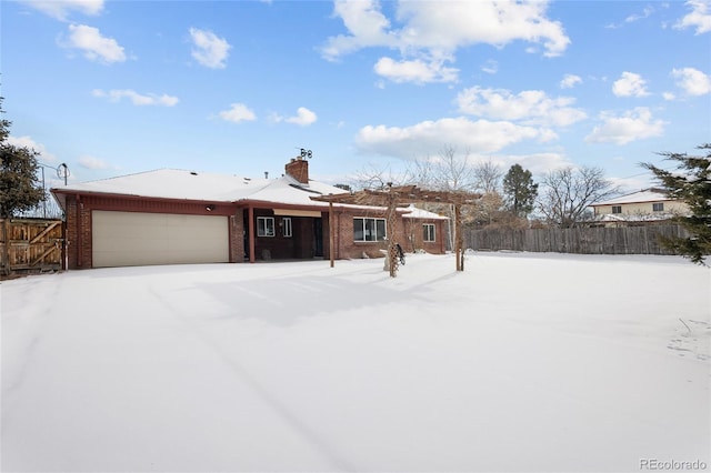 view of front of home with an attached garage, a chimney, fence, and brick siding