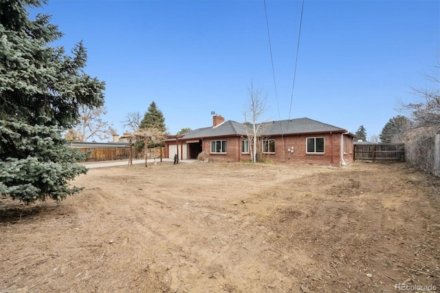 rear view of property featuring fence private yard, brick siding, and a chimney