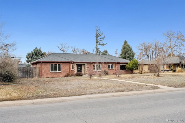 ranch-style house featuring fence and brick siding